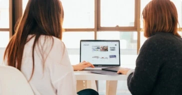 Two people talking around a laptop