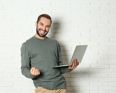 Man smiling and holding a laptop