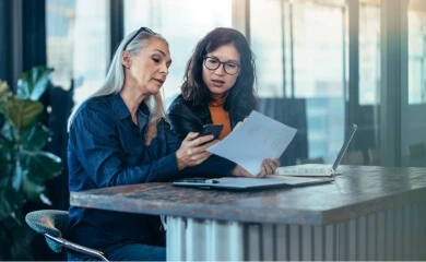 Two people stand at a table, discussing first hand knowledge searches